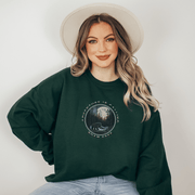 This gender neutral crewneck sweatshirt features a stunning design of a grizzly bear roaming on a campsite with the moon shining behind it. The saying "Adventure Is Calling Roam Free" is printed boldly, capturing the essence of the great outdoors and the spirit of camping. Perfect for any outdoor adventure