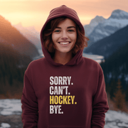 Introducing the must-have hoodie for any hockey player, fan, or enthusiast: the Sorry. Can't. Hockey. Bye. hoodie! Perfect for those chilly days at the rink or just lounging at home, this gender-neutral hoodie is sure to make everyone laugh. Featuring a bold and hilarious design with a nod to Canadian hockey culture, this funny hockey hoodie is a great gift for any hockey player.
